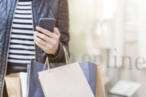 close up of woman hand holding shopping bags and looking her smart phone.close up.